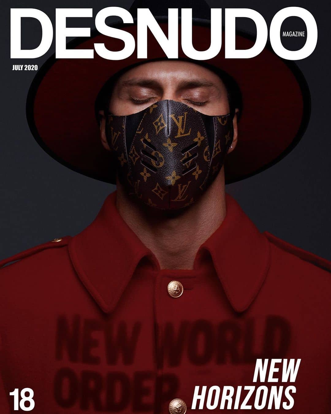 Kenny Braasch as the cover model of issue 18 of Desnudo Magazine wearing a Louis Vuitton mask, red jacket, and red-brimmed hat.